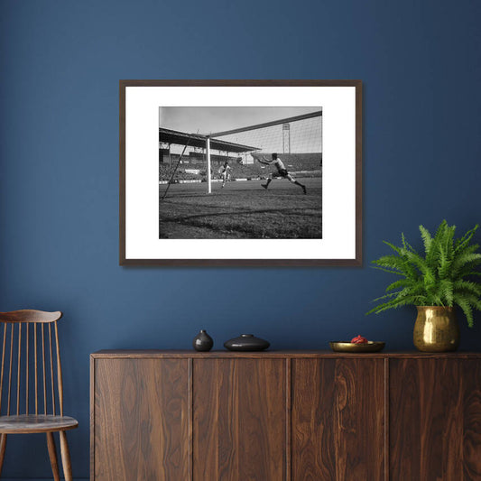 Zwart-witfoto uit 1965 van Johan Cruijff in actie tijdens een wedstrijd voor Ajax in Amsterdam. – donkerbruine wissellijst in woonkamer