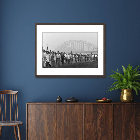 Zwart-witfoto uit 1986 van buitenlandse deelnemers aan de start van de Vierdaagse op de Waalbrug in Nijmegen. – donkerbruine wissellijst in woonkamer