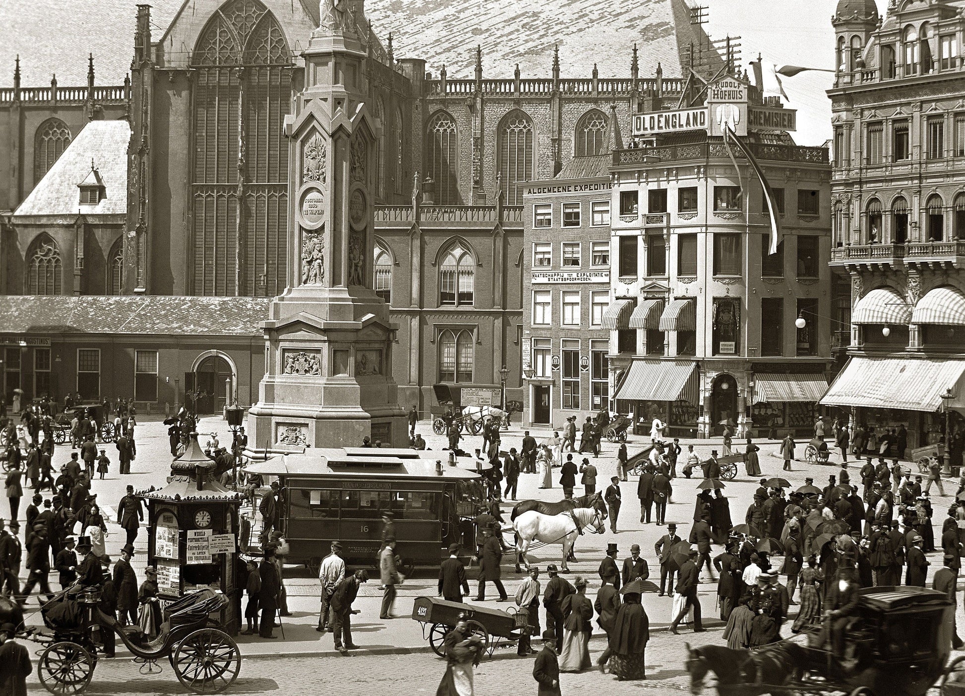 Zwart-witfoto uit 1895 van het Damplein in Amsterdam vol met mensen.