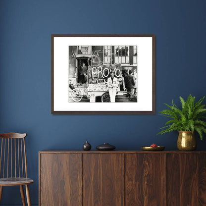 Zwart-witfoto uit 1967 van Provo Bernhard de Vries met zijn Witte Fietsenplan op de Dam in Amsterdam. – donkerbruine wissellijst in woonkamer