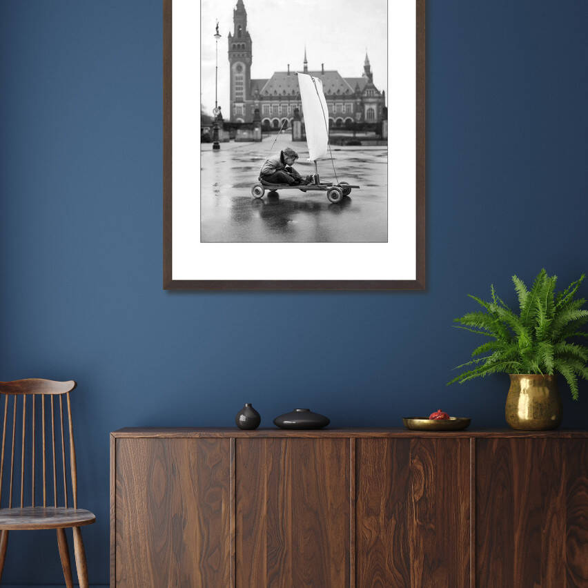Zwart-witfoto uit 1951 van een jongen die zich vermaakt in de Haagse Nieuwstraat in Den Haag. – donkerbruine wissellijst in woonkamer