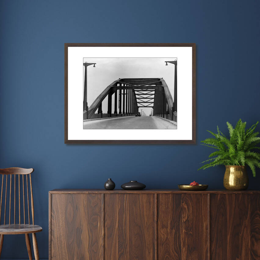 Zwart-witfoto uit omstreeks 1935 van de Rijnbrug bij Arnhem met een auto. – donkerbruine wissellijst in woonkamer