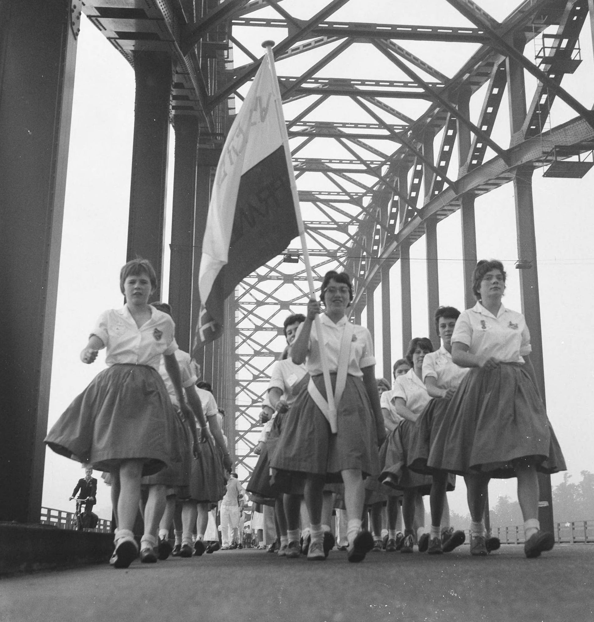 Zwart-witfoto uit 1960 van een wandelgroep meisjes tijdens de Vierdaagse op de Waalbrug in Nijmegen.