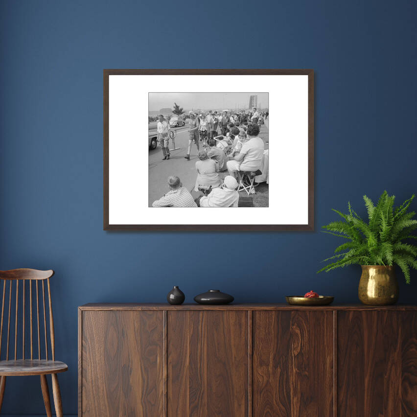 Zwart-witfoto uit 1961 van toeschouwers en lopers tijdens de Vierdaagse in Nijmegen met de Waalbrug op de achtergrond. – donkerbruine wissellijst in woonkamer
