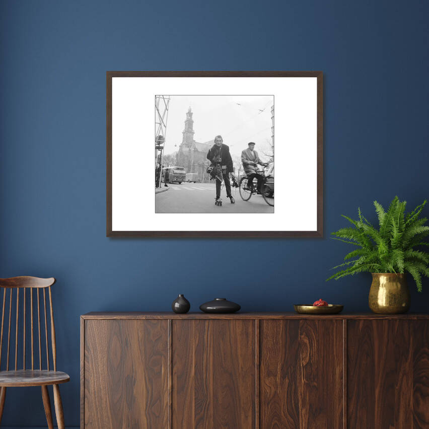 Zwart-witfoto uit 1966 van Anefo-fotograaf Jack de Nijs op rolschaatsen in Amsterdam. – donkerbruine wissellijst in woonkamer