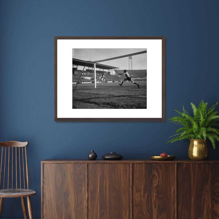 Zwart-witfoto uit 1965 van Johan Cruijff in actie tijdens een wedstrijd voor Ajax in Amsterdam. – donkerbruine wissellijst in woonkamer