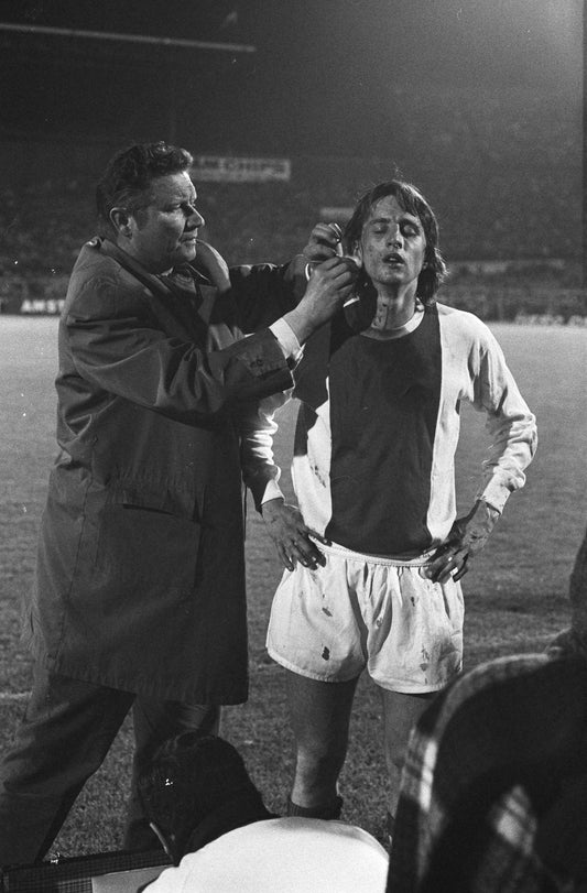 Zwart-witfoto uit 1971 van Johan Cruijff die wordt verzorgd door Ajax-clubarts Rolink in Amsterdam.