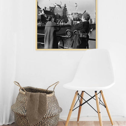 Zwart-witfoto uit 1954 van cineast Herman van der Horst die een vrouw filmt die meeuwen voert in Den Haag. – canvas naturel baklijst in keuken