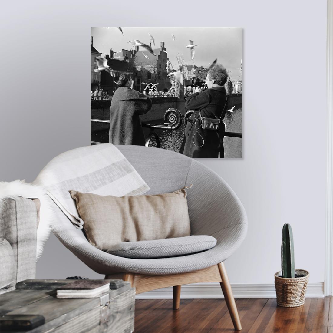 Zwart-witfoto uit 1954 van cineast Herman van der Horst die een vrouw filmt die meeuwen voert in Den Haag. – canvas zonder lijst in leeshoek
