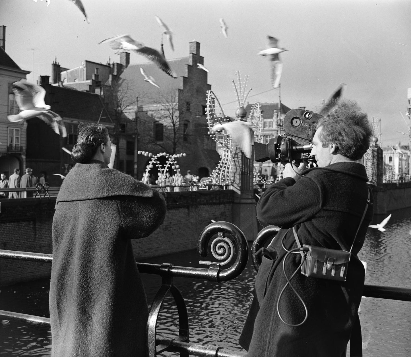 Zwart-witfoto uit 1954 van cineast Herman van der Horst die een vrouw filmt die meeuwen voert in Den Haag.
