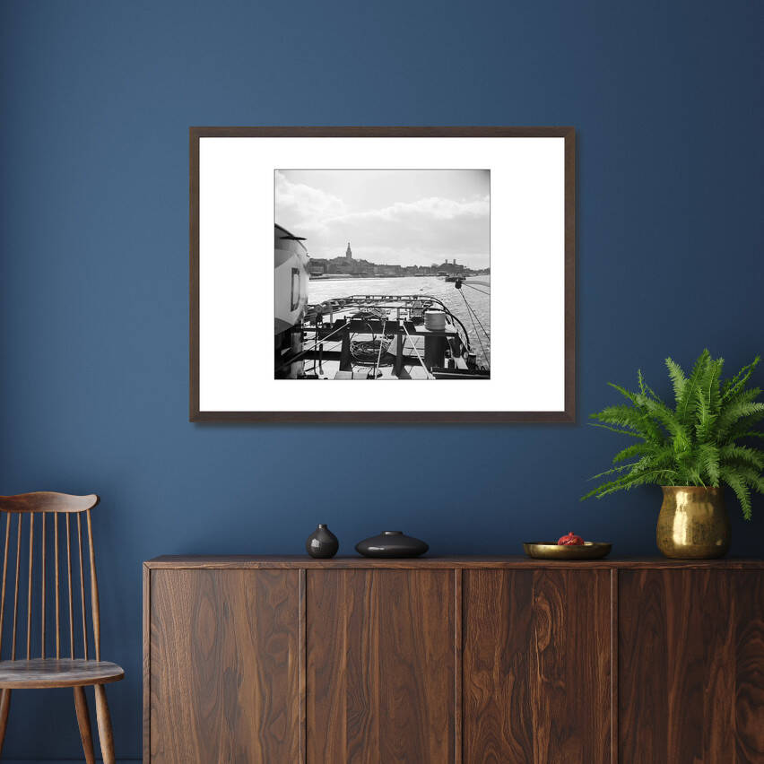 Zwart-witfoto uit 1955 van een sleep op de Waal bij Nijmegen met de Stevenskerk op de achtergrond. – donkerbruine wissellijst in woonkamer