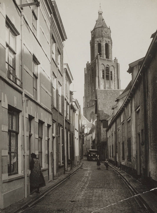 Zwart-witfoto van de Trompetsteeg in Arnhem met zicht op de toren van de Grote Kerk.
