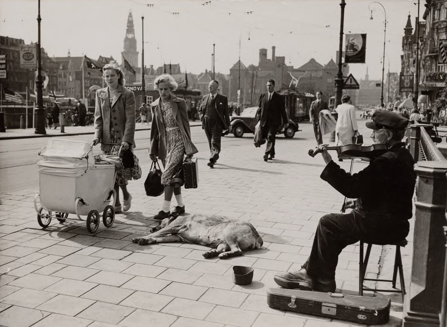 Zwart-witfoto uit 1950 van een straatviolist op een brug bij het Centraal Station in Amsterdam.