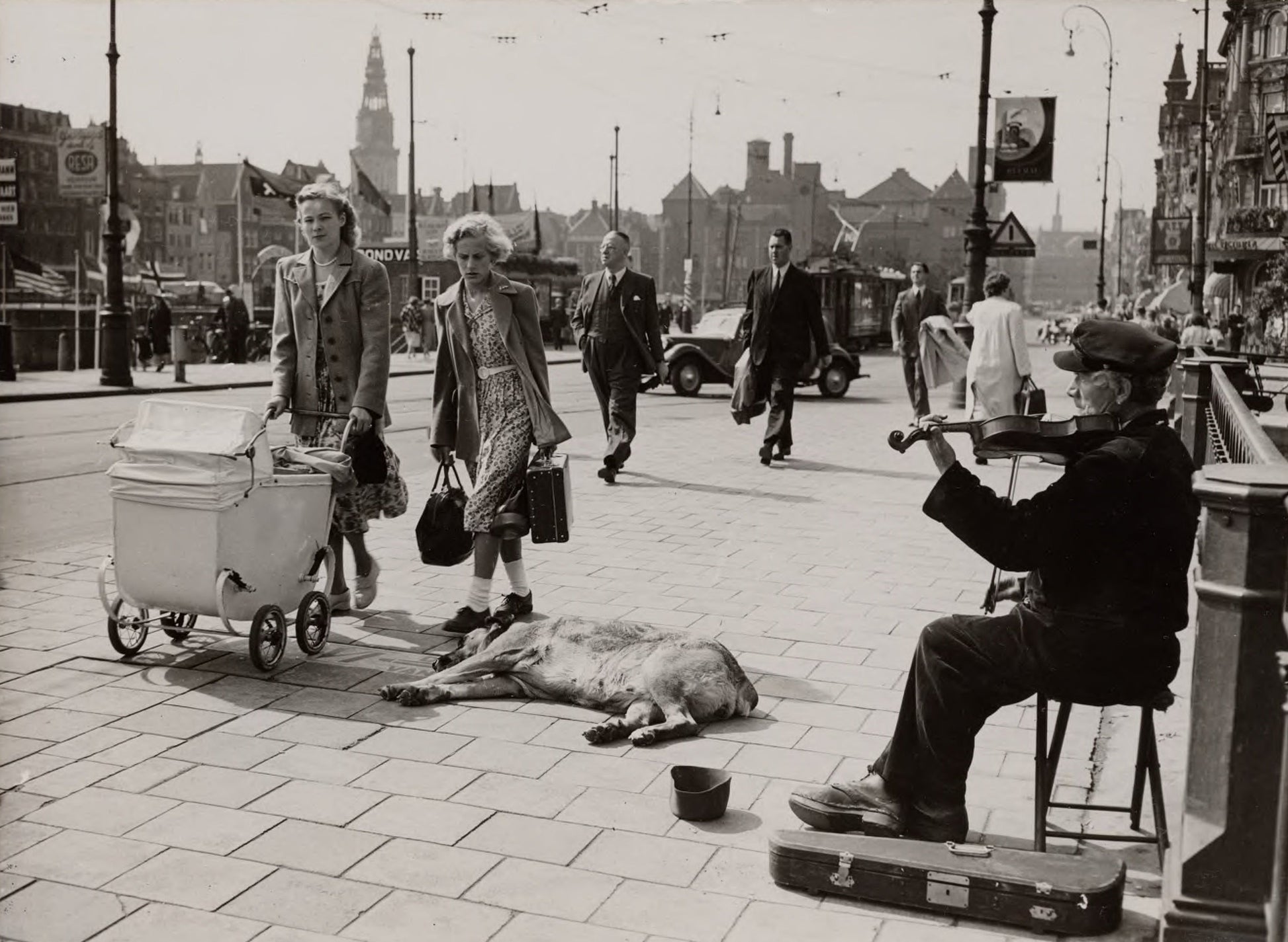 Zwart-witfoto uit 1950 van een straatviolist op een brug bij het Centraal Station in Amsterdam.