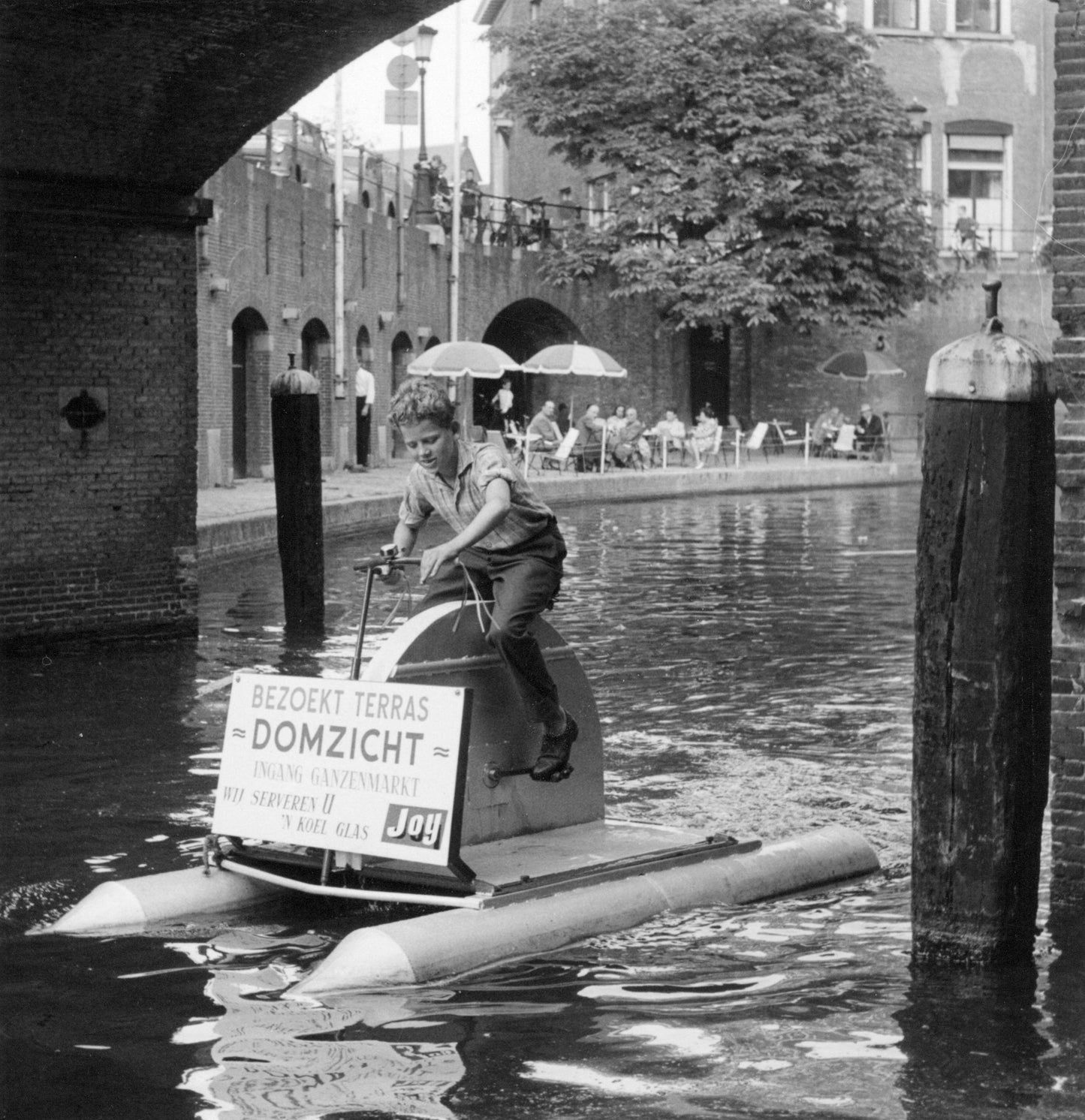 Zwart-witfoto uit 1960 van een jongen op een waterfiets in een Utrechtse gracht.