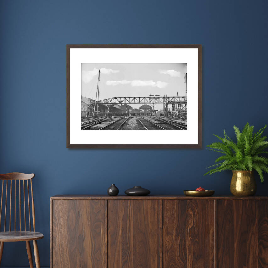 Zwart-witfoto uit 1904 van het plaatsen van een ijzeren hulpvoetbrug over de Oudegracht in Utrecht. – donkerbruine wissellijst in woonkamer